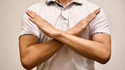 man saying no to asx shares by crossing arms in 'no deal' gesture