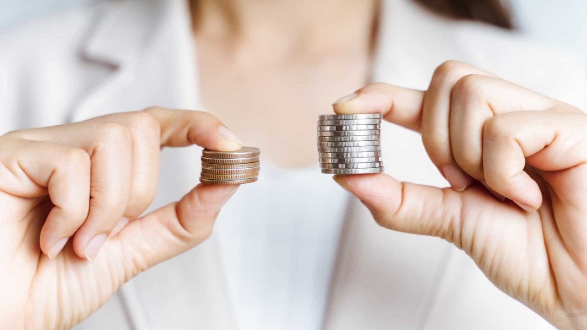 woman holdings small pile of coins representing brainchip share price and larger pile of coins