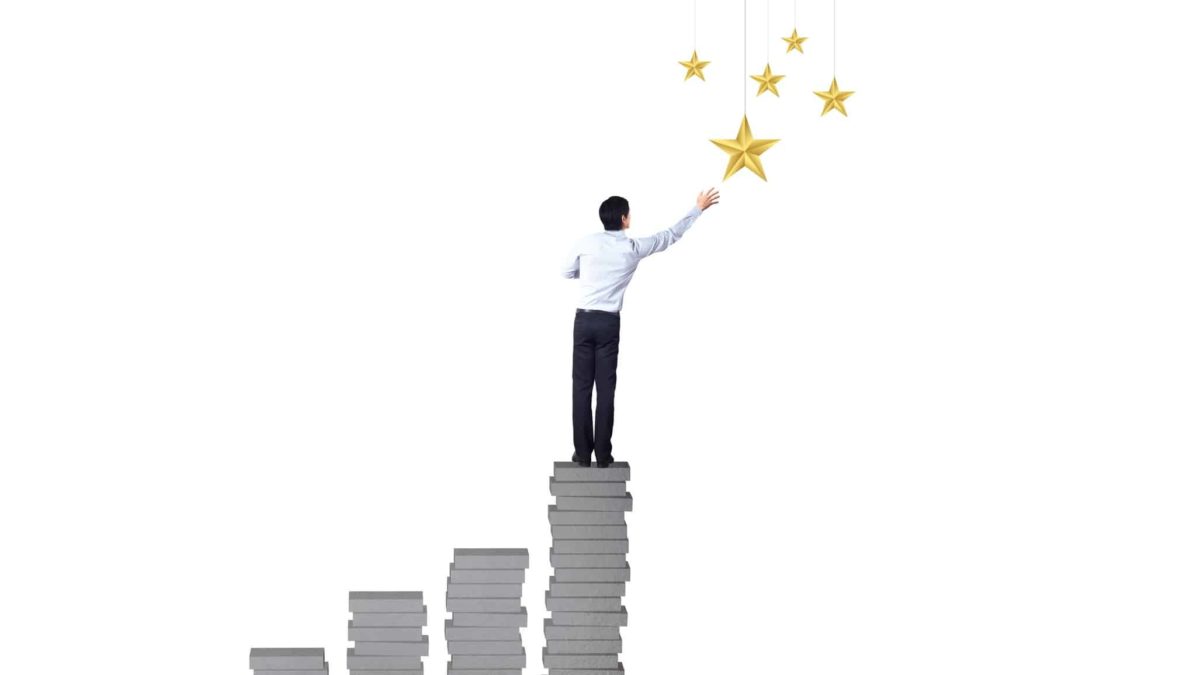 fund manager standing on increasing tiles of bricks reaching for the stars