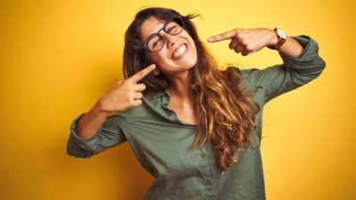 Surge in ASX share price represented by happy woman pointing to her big smile