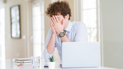 ASX share investor sitting in front of lap top with head in hands