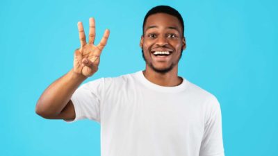 A man holds up his hand with 3 fingers up