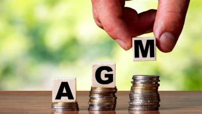 agm causing asx share price rise represented by letter blocks spelling agm on top of coin piles
