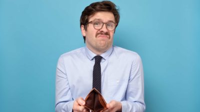 comparing bank savings to investing in asx shares represented by sad man turning out empty wallet