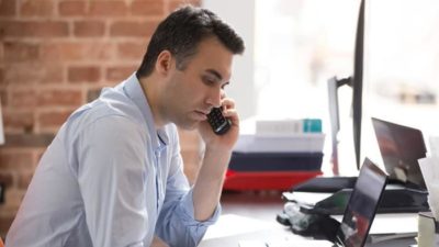 business man sitting and talking on phone whilst investing in asx shares