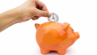 Sydney airport share price represented by hand placing a clock into a piggy bank