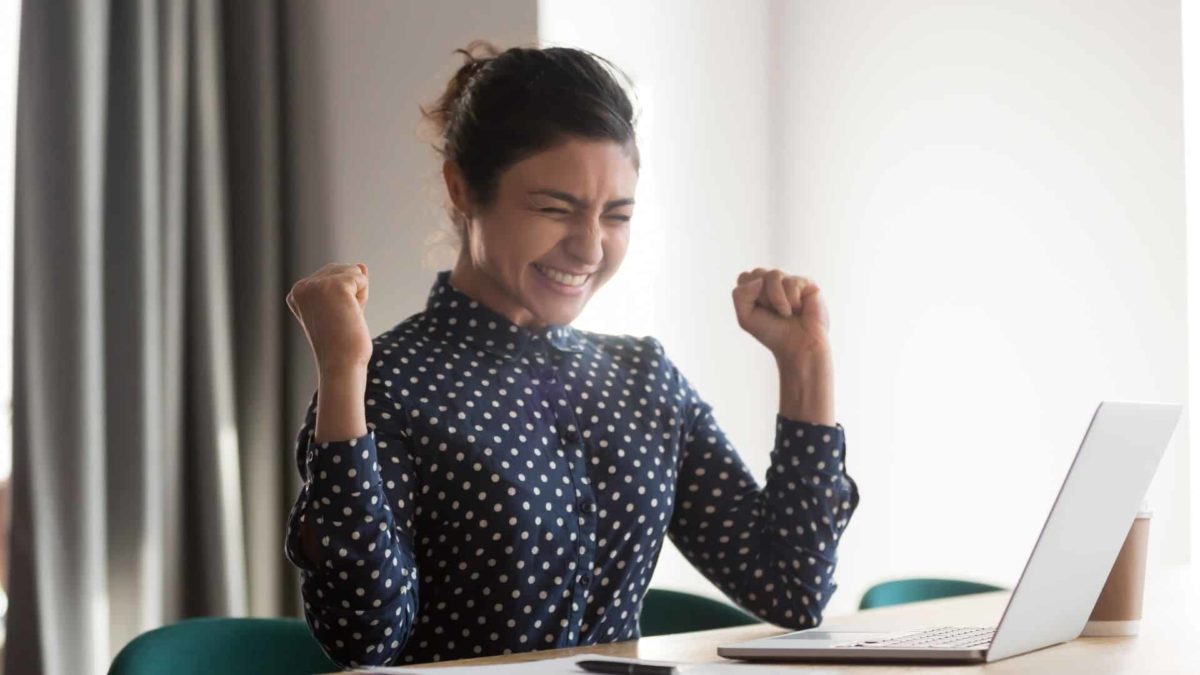 Happy investor looks at her computer to see the share price rise