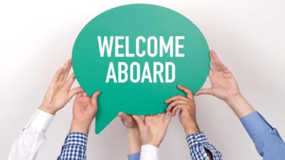 asx share initial public offering or IPO represented by hands holding up sign saying welcome aboard