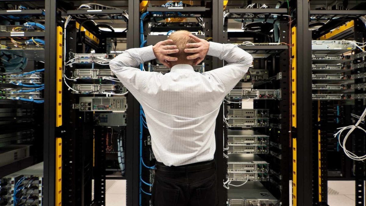 A stressed man with his hands on head trying to work out a major systems failure