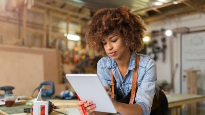 woman looking at asx share price rise on ipad whilst in workshop