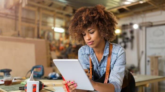 woman looking at asx share price rise on ipad whilst in workshop