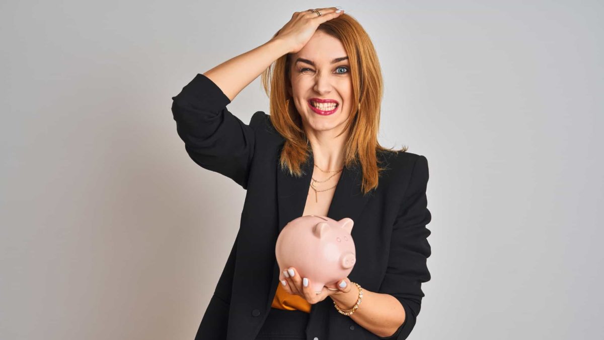 woman looking worried as she holds a piggy bank, indictating a share investor holding on amid a volatile ASX market