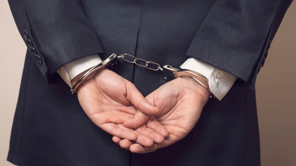 business man with hands handcuffed behind back