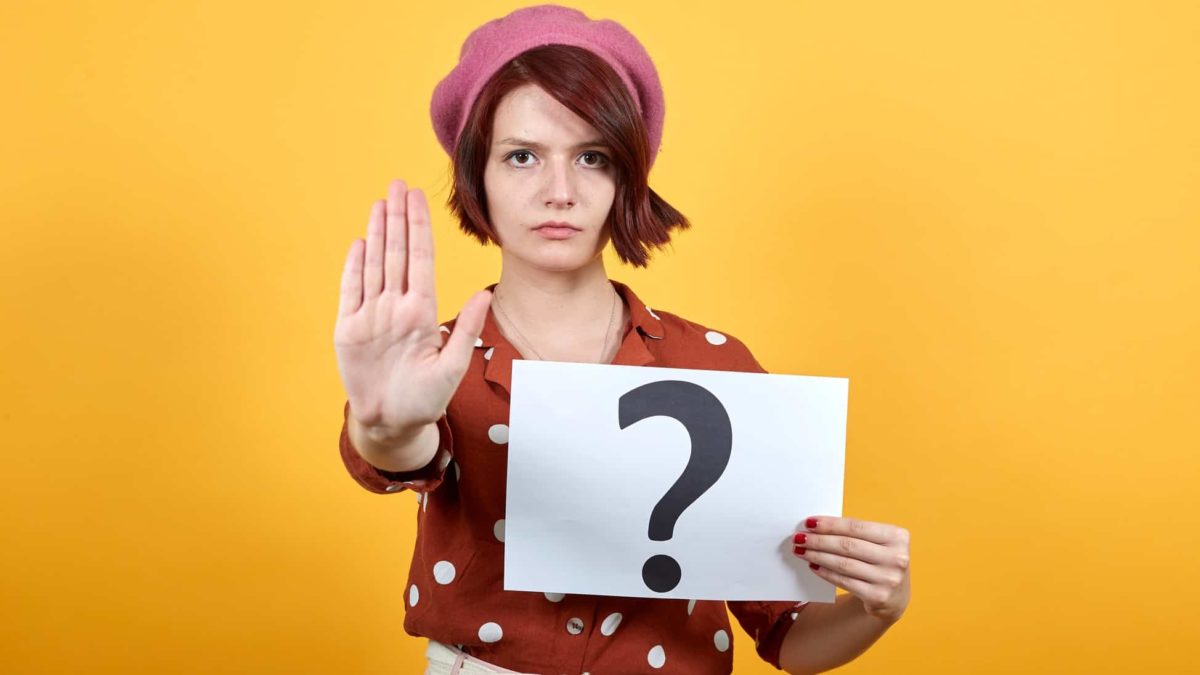A young woman holds her hand up in a stop sign with a sheet of paper in the other hand showing a question mark over the Pointerra share price today
