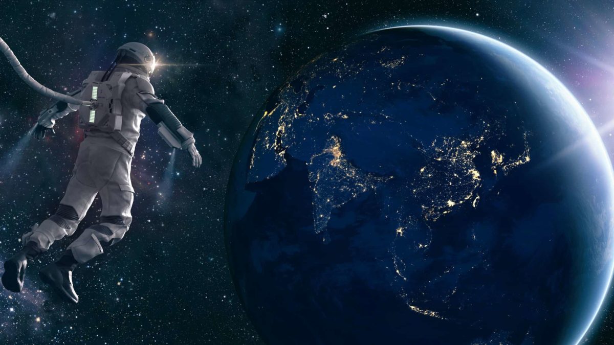 Astronaut floats in space looking down on Earth