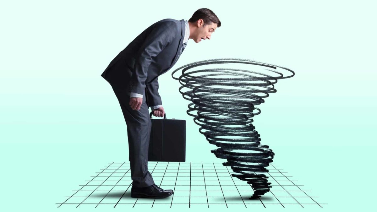 a businessman looks into a graph on the floor as a tornado rises, indicating share market chaos