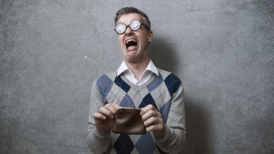 A man recoils from his empty wallet in horror, indicating a major share price fall.