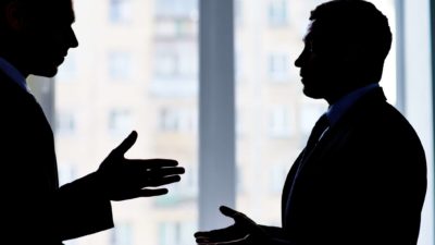 Two businessmen in silhouette, indicating a shady deal