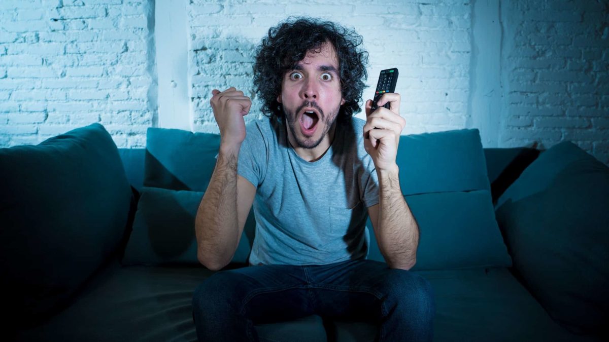 An excited fan watching a game of sports streamed live on TV