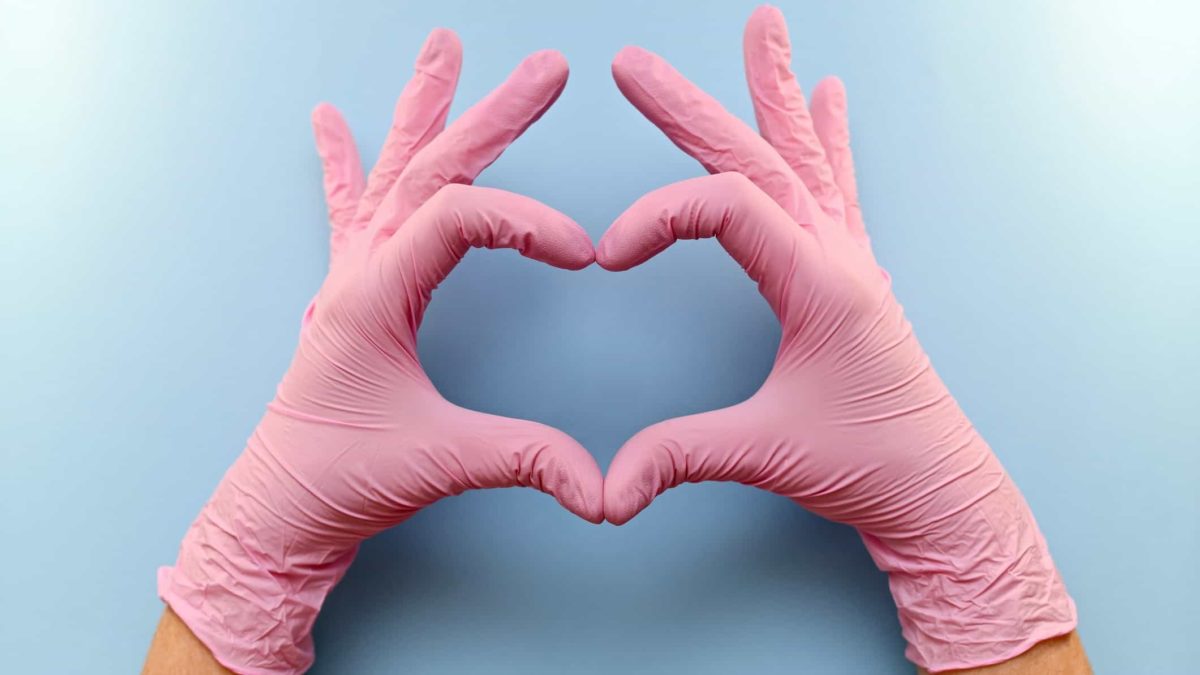 disembodied hands in pink surgical gloves making heart shape
