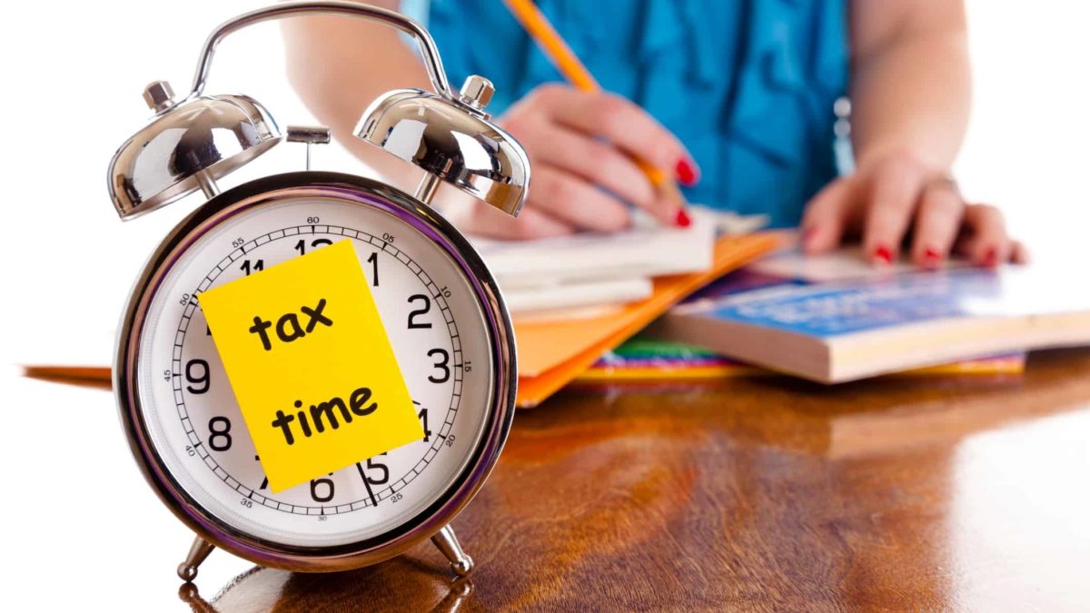 Clock with post it as a reminder of Tax Time