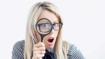 asx share price on watch represented by investor looking through magnifying glass