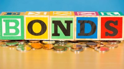 bond yields represented by wooden blocks spelling bonds atop coins