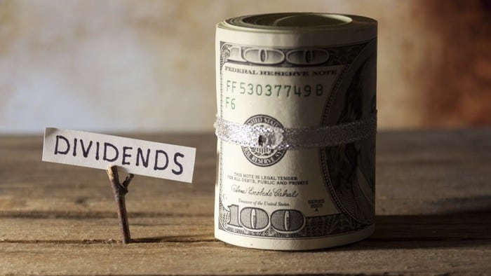 Dividend stocks represented by paper sign saying dividends next to roll of cash