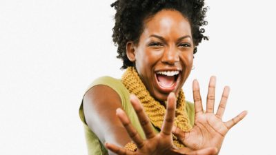 A laughing woman holds her hands up, indicating a share price racing higher ahead of a trading halt on the ASX market