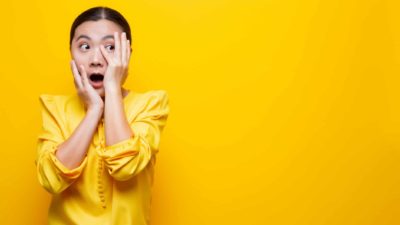 A nervous ASX shares investor holding her hands to her face fearing a global recession may occur