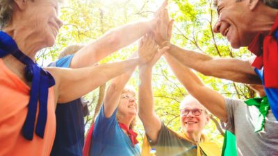 A group of people wearing capes join hands to celebrate, indicating a strong superannuation fund