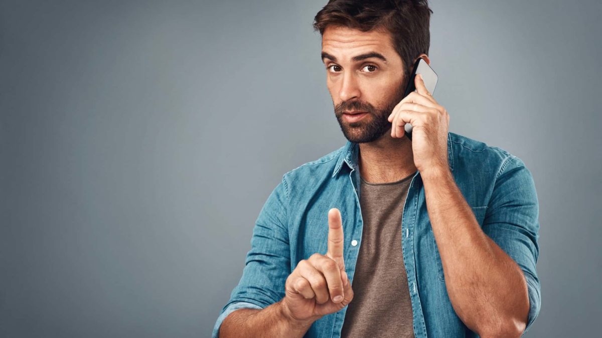 A man on a phone call points his finger, indicating a halt in trading on the ASX share market.