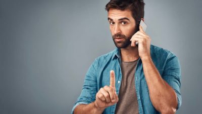 A man on a phone call points his finger, indicating a halt in trading on the ASX share market.