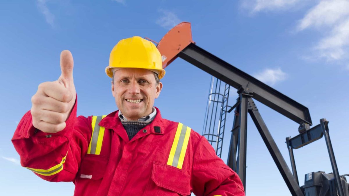 Monadelphous share price rio tintoA happy miner in front of a massive drilling rig, indicating a share price lift for ASX mining companies