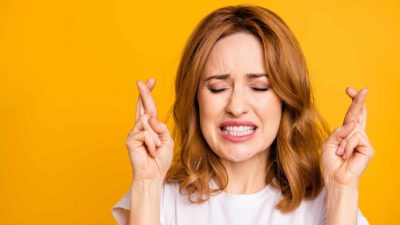 A woman nervously crosses her fingers, indicating hope for positive share price movement