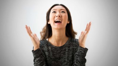 Happy woman cheering with hands in air after Mesoblast share price soars