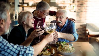 Happy retirees celebrate with wine over lunch