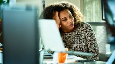 Woman with frustrated expression sits in front of a laptop