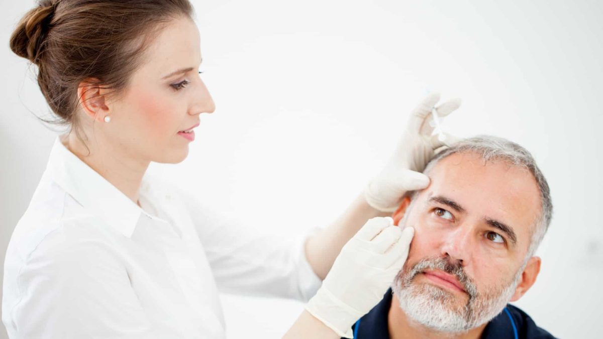 dermatologist looking closely at the skin on a man's face