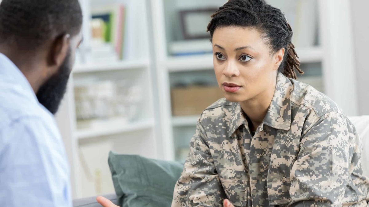 Army soldier looking sad and having conversation with her partner at home