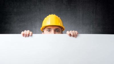builder peeking over board as if watching asx share price