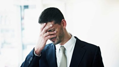 sad man with his hand over his face on news of the ASX share price falling