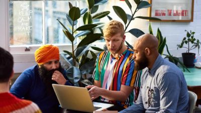 A discussion between colleagues using a laptop.
