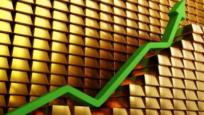 rising gold share price represented by a green arrow on piles of gold block