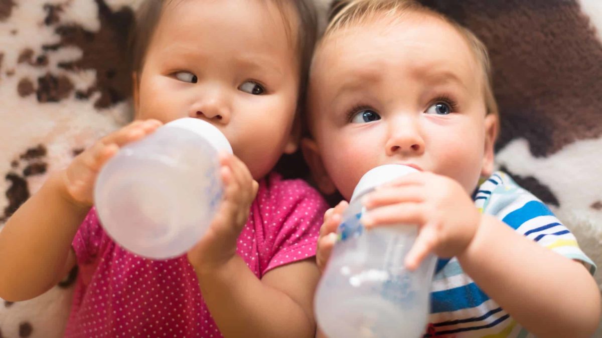 Two babies laying down together drink milk made with Bubs infant formula in bottles as the Bubs share price rises again today