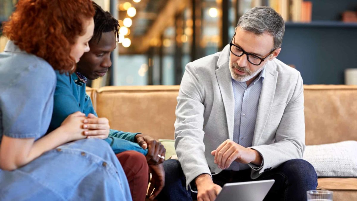 salesman explaining product on computer screen to couple