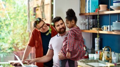 two dads and their daughter making dinner