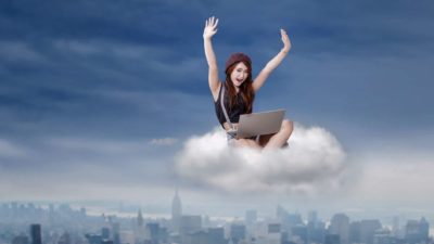 Woman using laptop sitting in cloud cheering