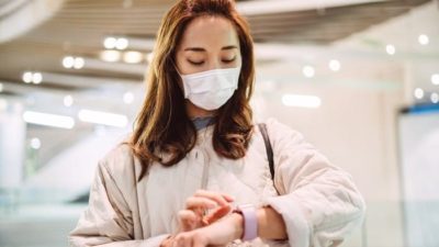 woman with a mask on looking at her apple watch