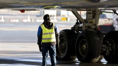 airline crew stands on tarmac under aircraft